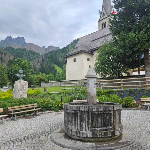 The church and fountain on Arabba's village square, wooded ridges behind