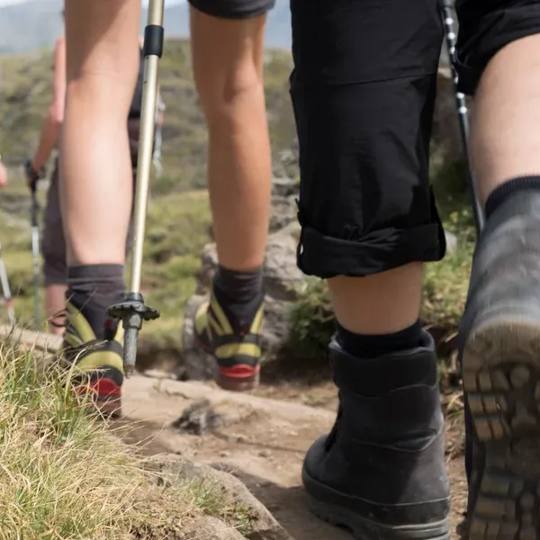 Boots de randonnée et trail runners côte à côte sur terrain alpin - le choix central pour les treks multi-jours dans les Dolomites