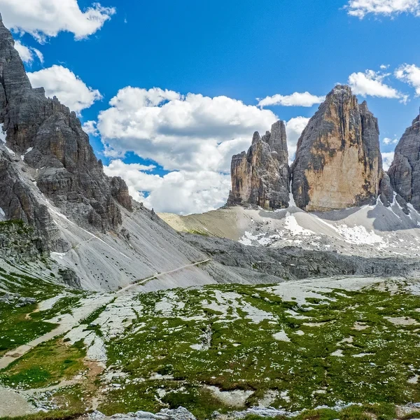 Cinque Torri rock towers with green meadows and Dolomite peaks in the background