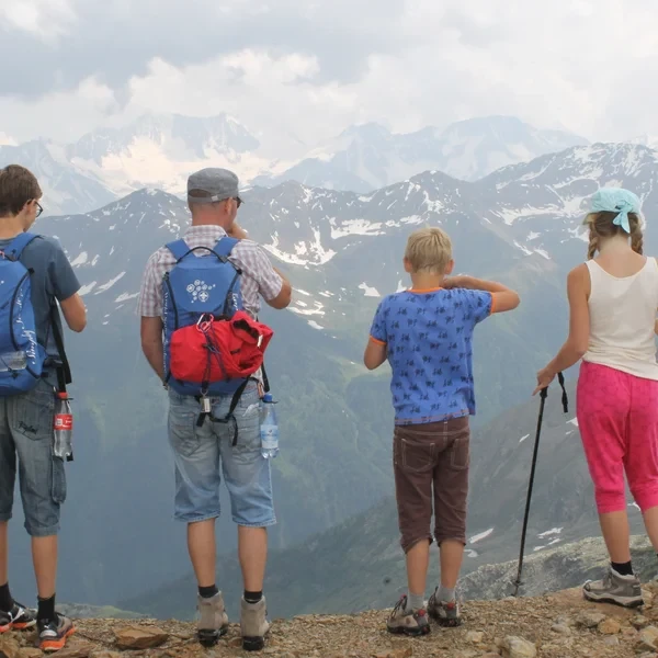 Jeune enfant qui randonne sur un large sentier de montagne dans les Dolomites, avec une prairie alpine et des sommets calcaires dentelés en arrière-plan