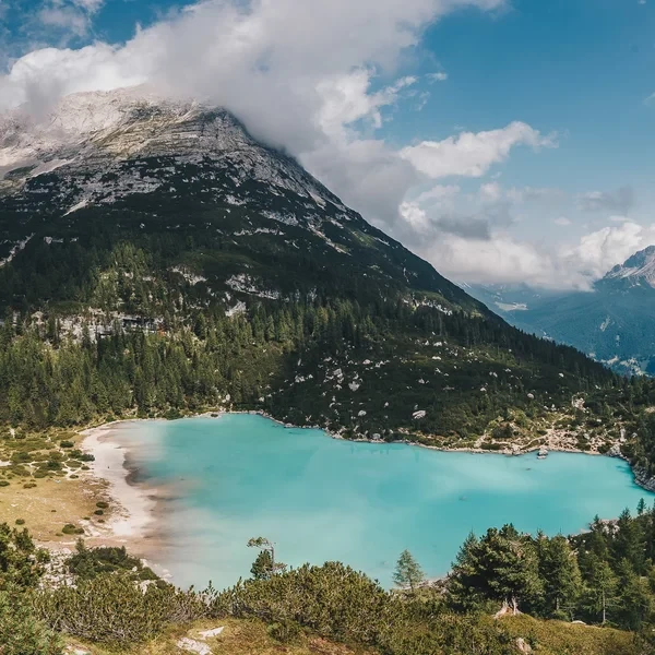 Turquoise glacial water of Lago di Sorapis with the Dito di Dio rock spire rising from the southeast shore