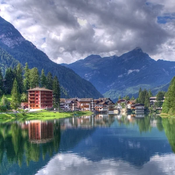 Le lac d'Alleghe reflétant les façades colorées du village et les sommets dolomitiques environnants