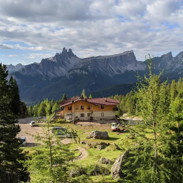 Rifugio Angelo Dibona with parking area below jagged Tofane peaks and dense conifer forest