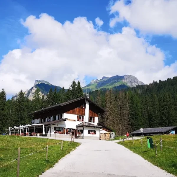 Rifugio Aquileia lodge with wooden balconies beneath rugged sunlit mountains in Selva di Cadore