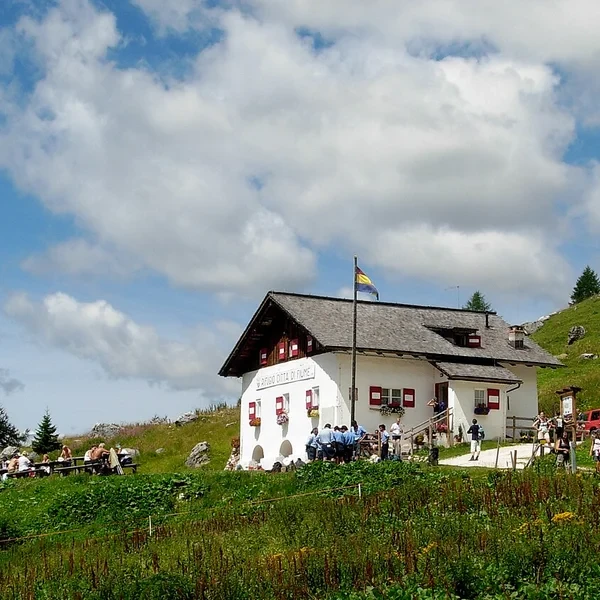 Rifugio Citta di Fiume on a grassy slope below Monte Pelmo under overcast skies