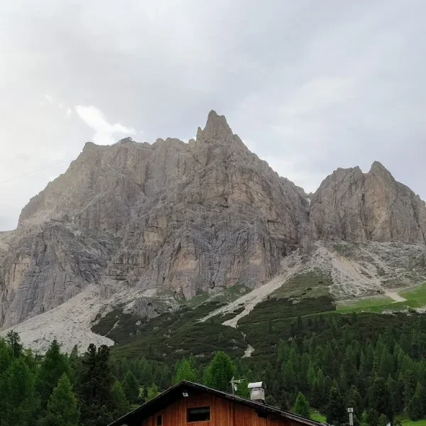 Rifugio Col Gallina with outdoor seating terrace below Tofane rocky peaks and green forest