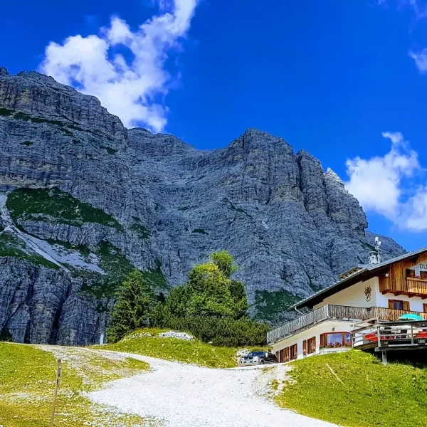 Rifugio Duca d Aosta with outdoor seating below the steep Tofane rock walls