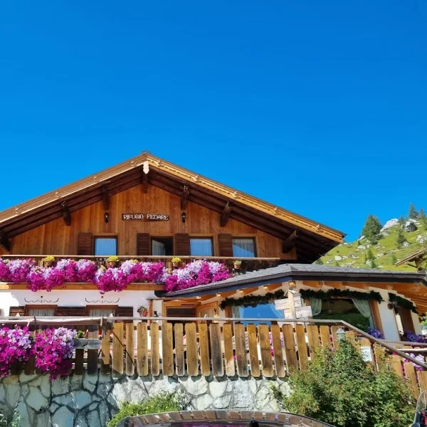 Rifugio Fedare entrance with flowers on the steps and a mountain biker resting outside