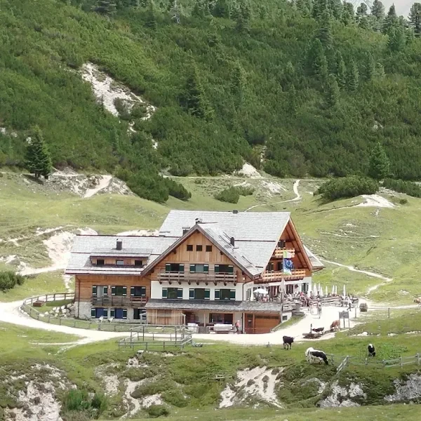 Rifugio Fodara Vedla with solar panels in a remote grassy alpine setting under blue sky
