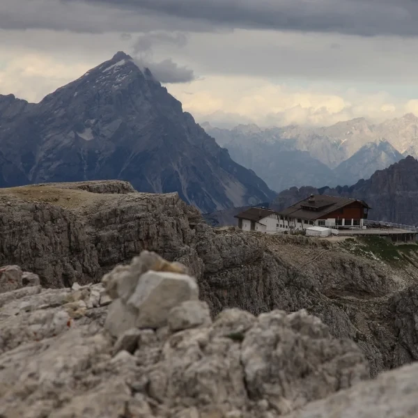 Rifugio Lagazuoi perched on a rocky ridge above Passo Falzarego with jagged Dolomite peaks behind
