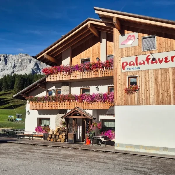 Rifugio Palafavera with flower boxes on the balcony against a backdrop of grey Civetta peaks