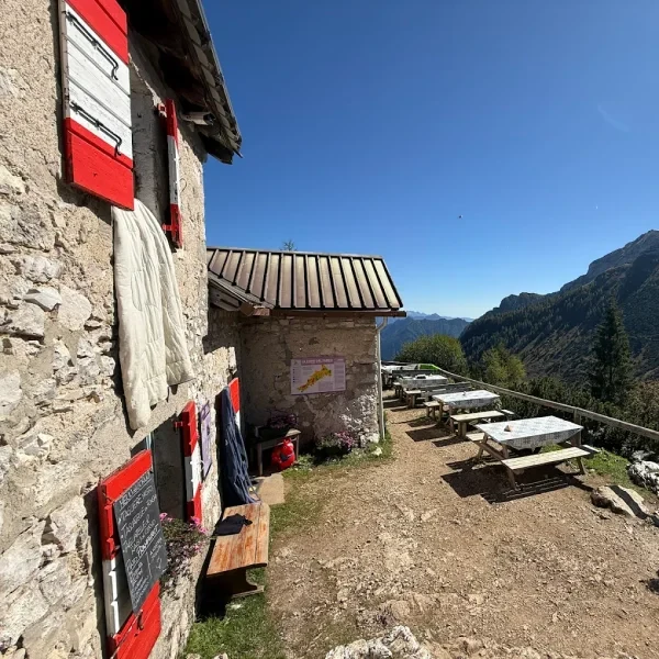 Rifugio Sommariva al Pramperet below steep rocky cliffs with a hiking path leading to the entrance