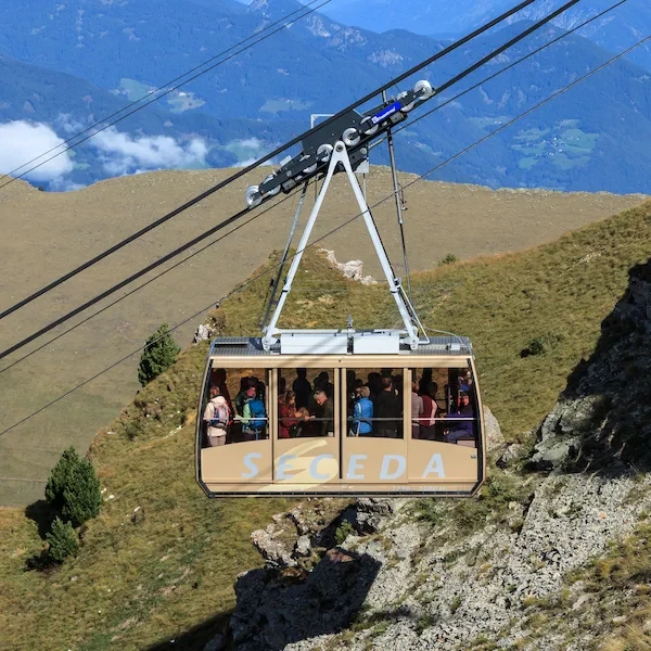 The Seceda gondola cable car carrying passengers above green slopes in Val Gardena